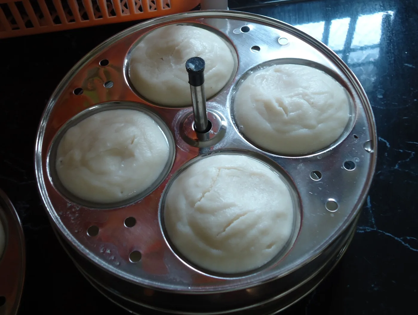 Steamed idlis still in the cooker plate.